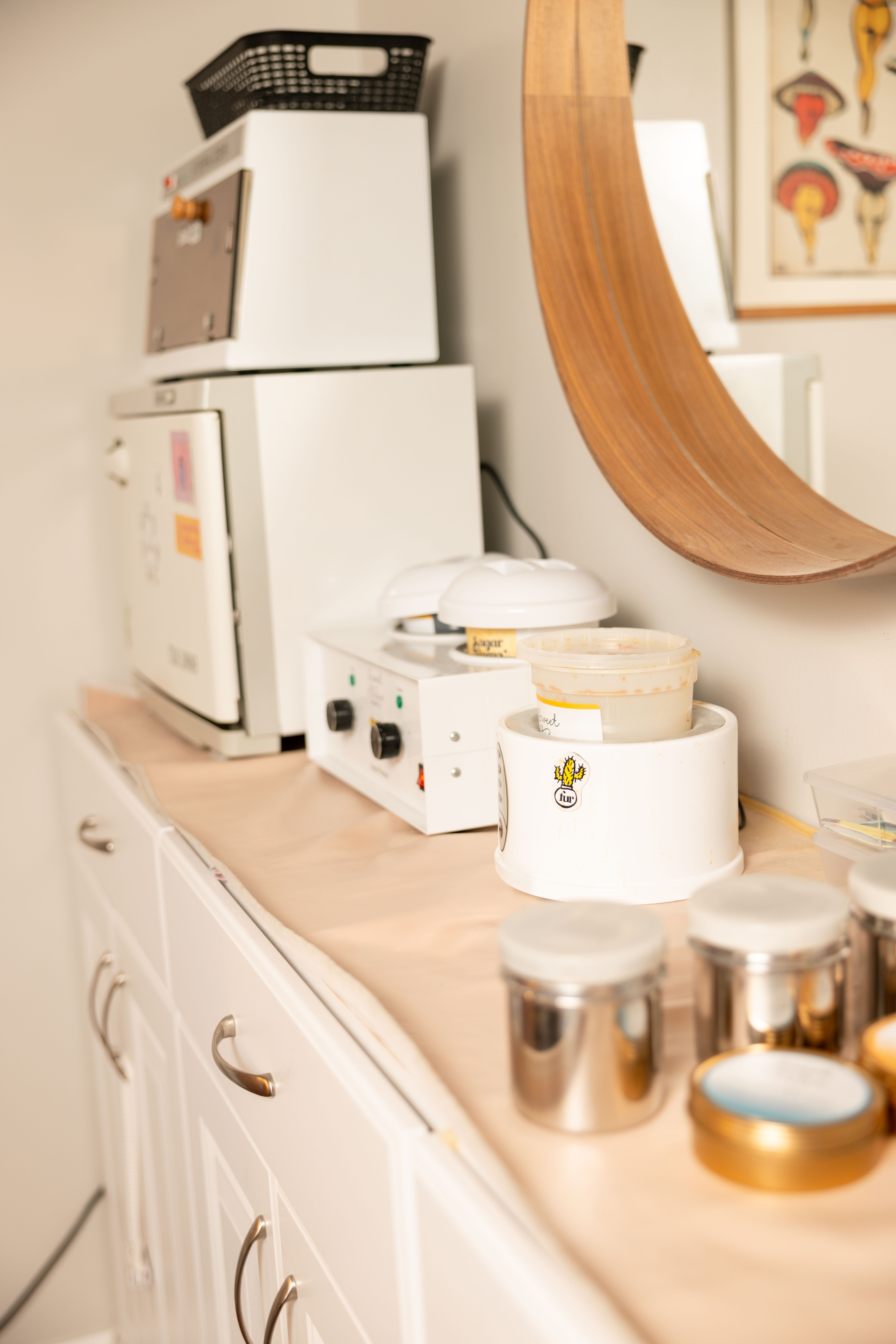 Sola's studio counter: sugar and wax warmers beneath a wooden arched mirror
