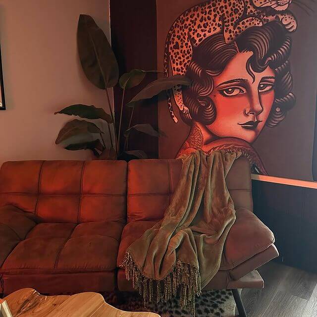 A corner of the studio with its mural and a leather couch, lit warm